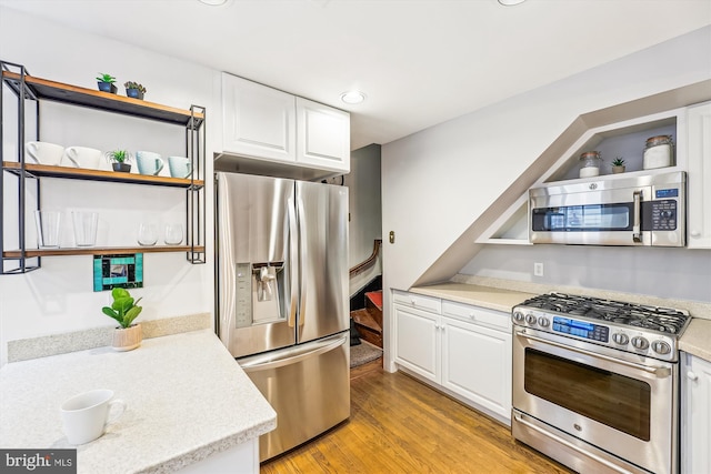 kitchen featuring stainless steel appliances, white cabinetry, and light hardwood / wood-style flooring