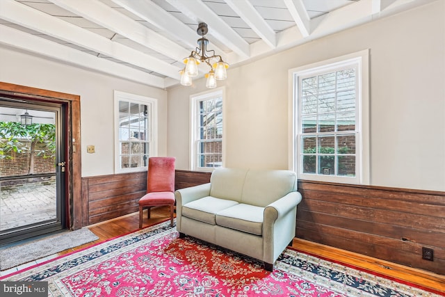 living area featuring a healthy amount of sunlight, a chandelier, and beam ceiling