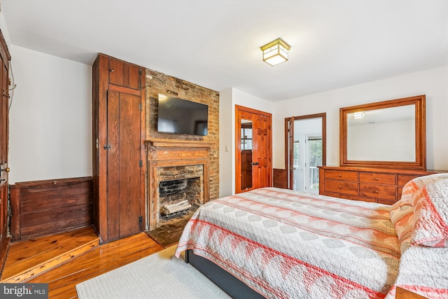 bedroom featuring light hardwood / wood-style floors and a brick fireplace