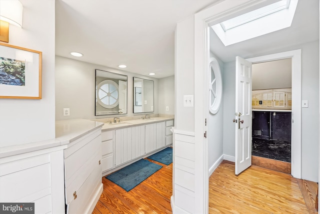 bathroom featuring vanity, wood-type flooring, and a skylight