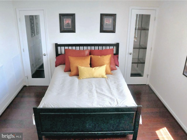 bedroom with dark wood-type flooring, connected bathroom, and french doors