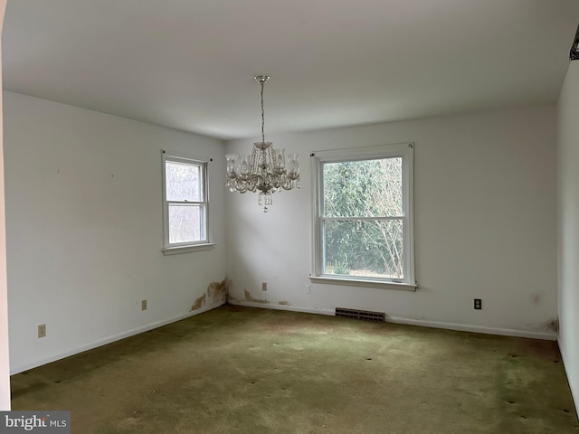 carpeted spare room featuring an inviting chandelier