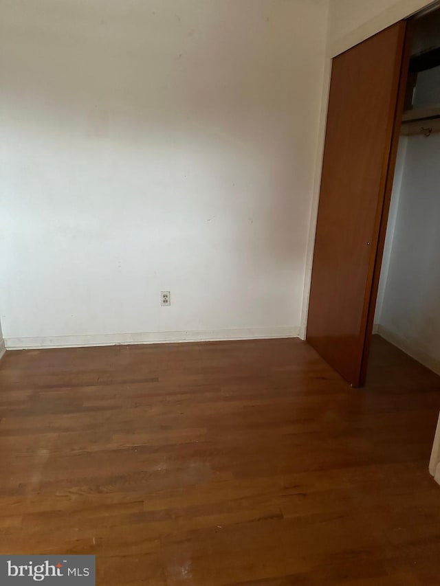 unfurnished bedroom featuring dark hardwood / wood-style flooring and a closet