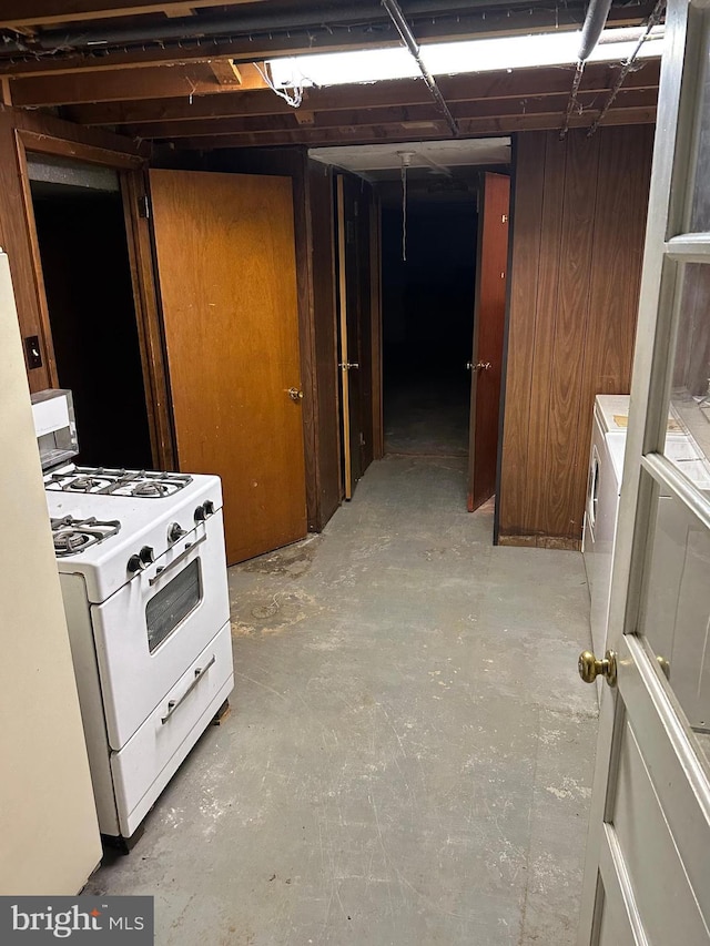 interior space featuring washer / clothes dryer, wooden walls, and white range with gas stovetop