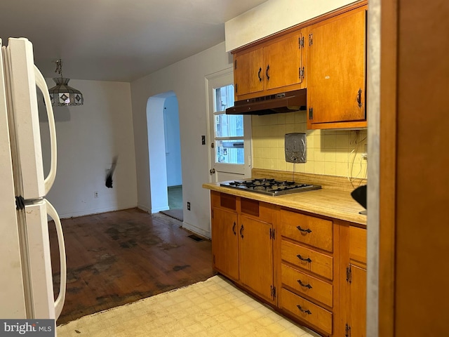 kitchen with white refrigerator, stainless steel gas cooktop, light wood-type flooring, and tasteful backsplash