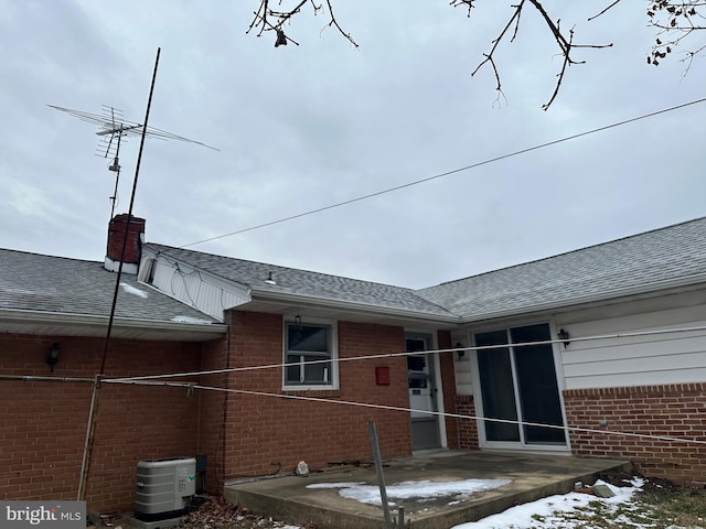 snow covered house featuring a patio and central AC unit