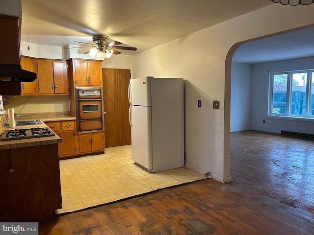 kitchen featuring white fridge, wall oven, light wood-type flooring, stainless steel gas cooktop, and ceiling fan