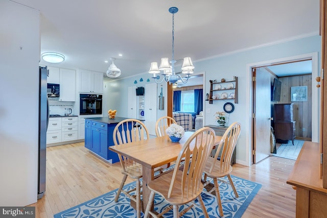 dining room featuring an inviting chandelier, ornamental molding, and light wood-type flooring