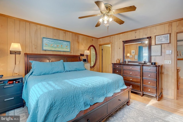 bedroom featuring crown molding, ceiling fan, light hardwood / wood-style flooring, and wood walls