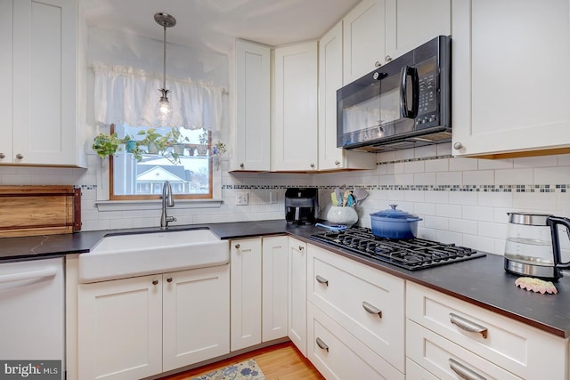 kitchen featuring pendant lighting, sink, white cabinets, decorative backsplash, and black appliances