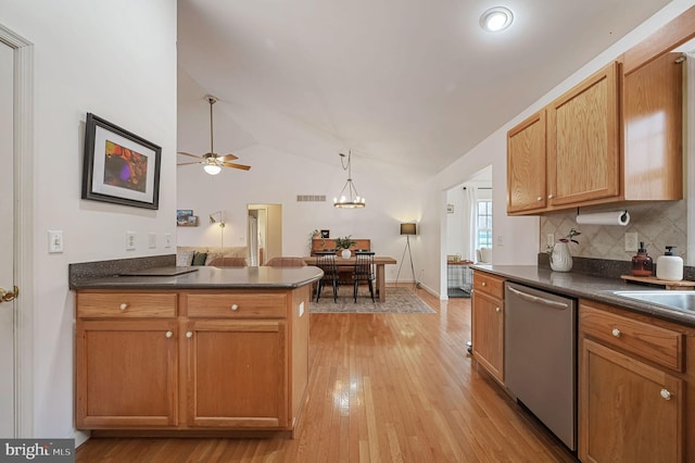 kitchen featuring pendant lighting, light hardwood / wood-style flooring, dishwasher, tasteful backsplash, and vaulted ceiling