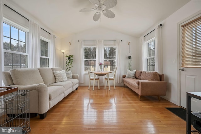 living room featuring vaulted ceiling, ceiling fan, light hardwood / wood-style floors, and a wealth of natural light