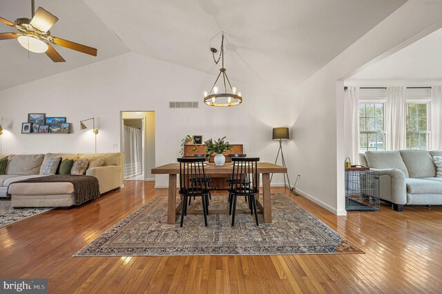 dining area featuring hardwood / wood-style flooring, ceiling fan with notable chandelier, and vaulted ceiling