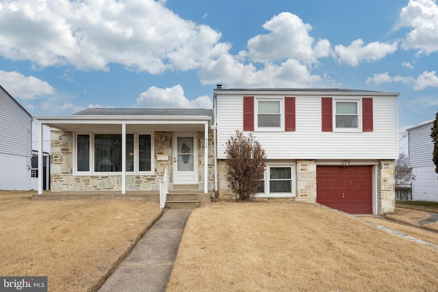 tri-level home featuring a front lawn, a garage, and covered porch