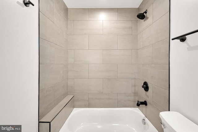 bathroom with toilet and tiled shower / bath