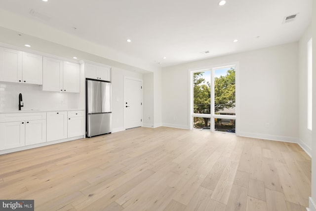 unfurnished living room featuring sink and light wood-type flooring