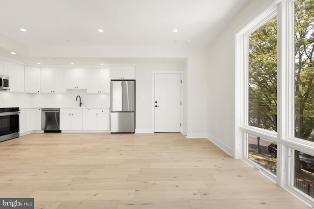 kitchen with sink, white cabinetry, light hardwood / wood-style floors, and appliances with stainless steel finishes