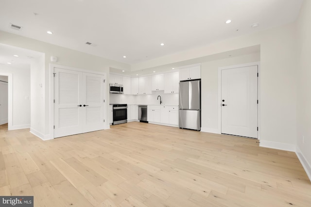 kitchen featuring sink, white cabinetry, light hardwood / wood-style flooring, and appliances with stainless steel finishes