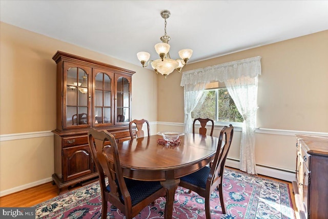 dining space with baseboard heating, light hardwood / wood-style floors, and a chandelier