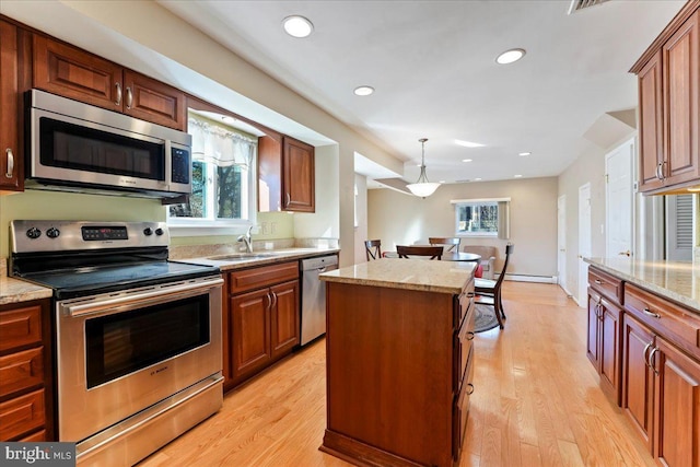 kitchen featuring stainless steel appliances, sink, light stone counters, light hardwood / wood-style flooring, and a kitchen island