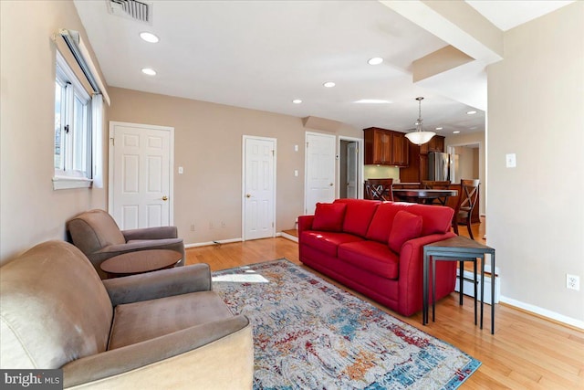 living room with a baseboard heating unit and light wood-type flooring