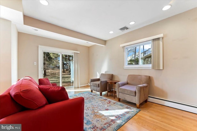 living room featuring hardwood / wood-style floors, a wealth of natural light, and a baseboard heating unit