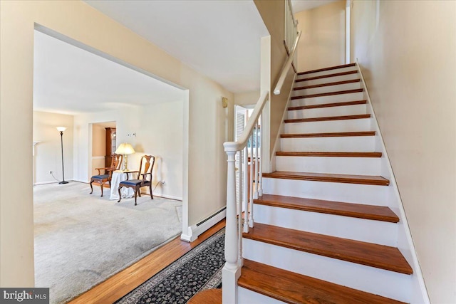 stairway with baseboard heating and wood-type flooring