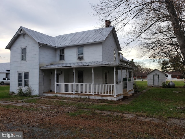 view of front of house featuring covered porch, a front lawn, and a storage shed