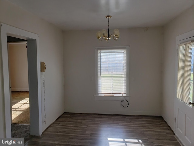 spare room featuring a notable chandelier and dark hardwood / wood-style floors