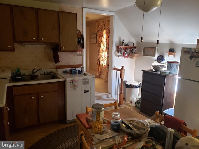 kitchen featuring sink, white fridge, and lofted ceiling