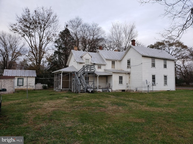 rear view of property featuring a yard and a sunroom