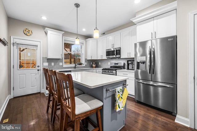 kitchen with a kitchen island, white cabinetry, stainless steel appliances, tasteful backsplash, and hanging light fixtures