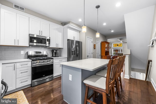 kitchen featuring hanging light fixtures, white cabinets, decorative backsplash, and appliances with stainless steel finishes