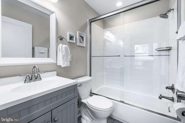 full bathroom with toilet, bath / shower combo with glass door, and vanity