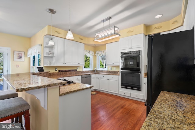 kitchen with black appliances, white cabinetry, a kitchen breakfast bar, decorative light fixtures, and kitchen peninsula