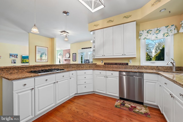 kitchen with appliances with stainless steel finishes, sink, white cabinets, light wood-type flooring, and a wealth of natural light