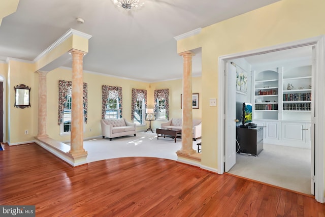 unfurnished living room featuring decorative columns, wood-type flooring, built in features, and ornamental molding