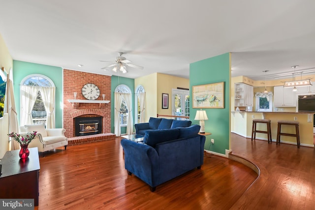 living room with ceiling fan, dark hardwood / wood-style floors, and a brick fireplace