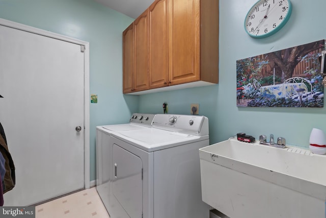 clothes washing area featuring sink, cabinets, and washer and clothes dryer