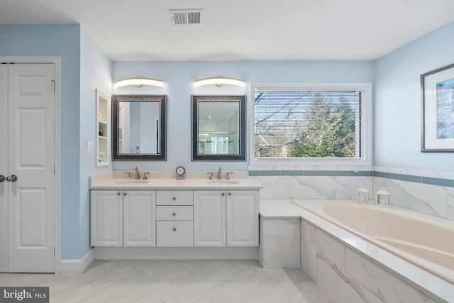 bathroom with tiled tub and vanity