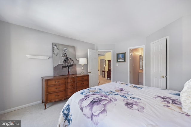 bedroom with ensuite bathroom and light carpet