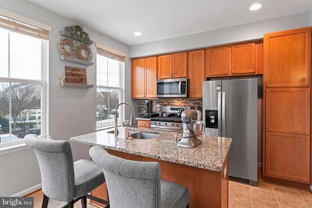 kitchen with light stone counters, a healthy amount of sunlight, a sink, stainless steel appliances, and backsplash