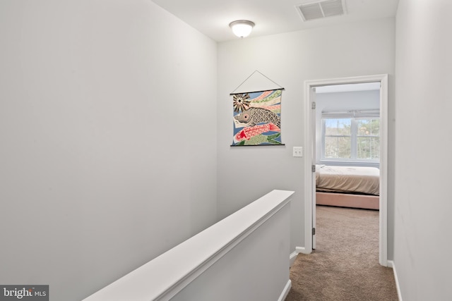 hallway with visible vents, baseboards, and carpet