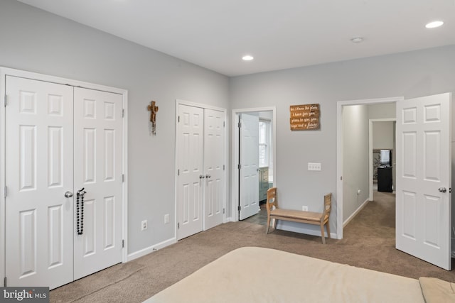 carpeted bedroom featuring recessed lighting, baseboards, and multiple closets