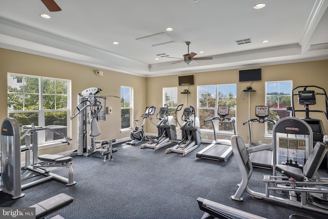 gym with visible vents, ceiling fan, crown molding, and a tray ceiling