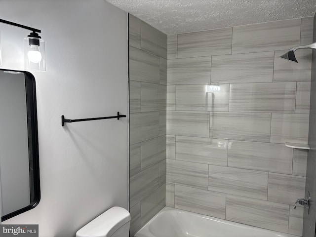 bathroom with toilet, tiled shower / bath combo, and a textured ceiling