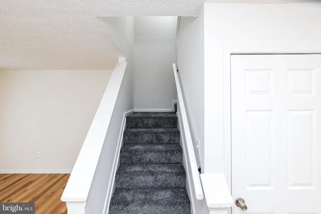 stairway featuring a textured ceiling and hardwood / wood-style floors