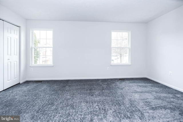 spare room featuring dark colored carpet