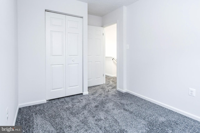 unfurnished bedroom with a closet and dark carpet