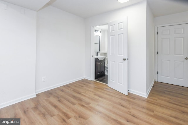 unfurnished bedroom featuring light hardwood / wood-style floors and connected bathroom